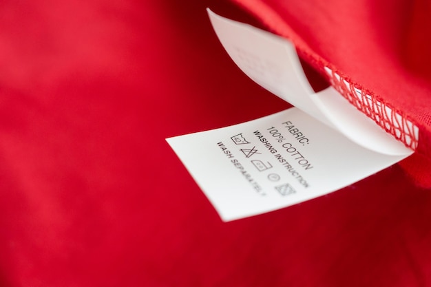 Instructions de lavage du linge blanc sur l'étiquette des vêtements sur chemise en coton rouge