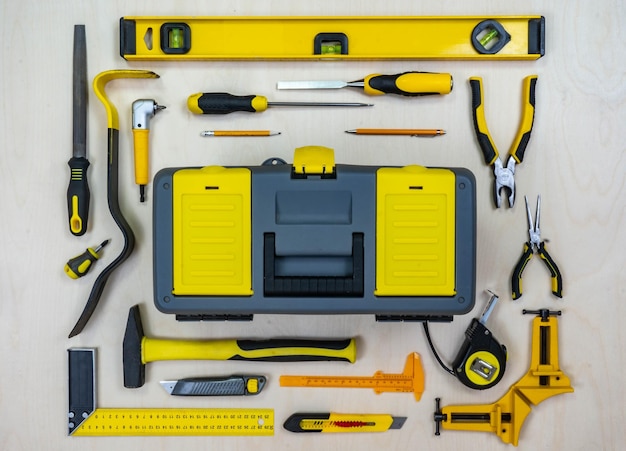 Instruments de construction et une boîte à outils sur fond de contreplaqué Tous les outils et une boîte avec des éléments jaunes