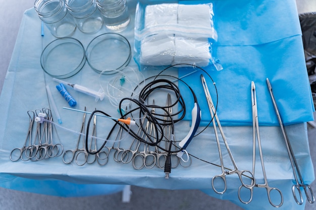 Photo instruments et outils chirurgicaux, y compris scalpels, forceps et pincettes. outils de chirurgie disposés sur une table en salle d'opération.