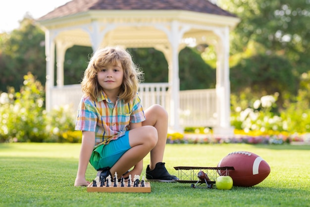 Intelligent concentré et pensant enfant garçon jouant aux échecs enfant jouant aux échecs et s'amusant en plein air sur b