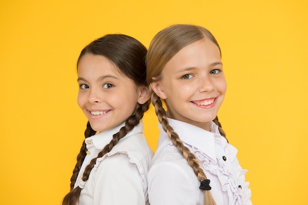 Intelligent et intelligent. mode formelle enfant. Éducation à l'étranger. des enfants à l'allure intelligente. copains d'école. enfants heureux en uniforme. petites filles sur fond jaune. amitié et fraternité. meilleurs amis.