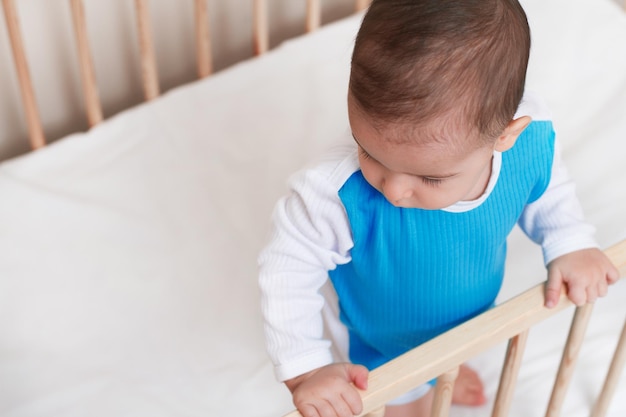 Intéressant bébé tout-petit dans le lit blanc