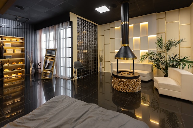 Intérieur d'appartement masculin élégant et moderne sombre avec éclairage, murs décoratifs, cheminée, dressing et immense fenêtre
