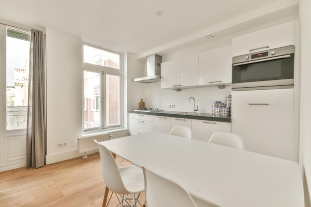 L'intérieur d'un appartement moderne avec une cuisine et un coin repas en blanc sur un parquet