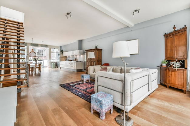 Intérieur d'appartement moderne avec un grand canapé gris, un espace salle à manger et un escalier menant au deuxième étage