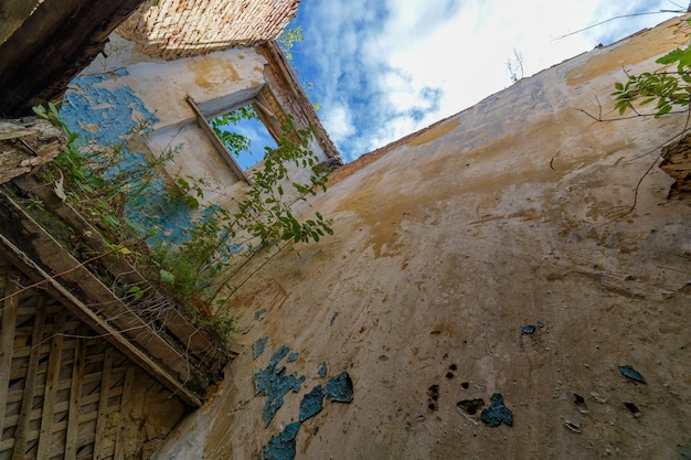 Intérieur de bâtiment de dortoir abandonné avec grand mur minable et pas de toit avec ciel bleu et nuages