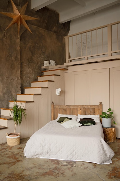 L'intérieur d'une chambre à coucher moderne avec un lit blanc et des escaliers en bois