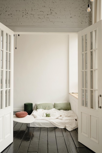 L'intérieur d'une chambre à coucher avec un mur blanc et un sol en bois