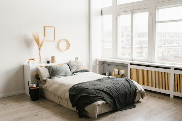 Intérieur de la chambre dans un style minimaliste scandinave dans un schéma de couleurs blanc et gris avec de grandes fenêtres