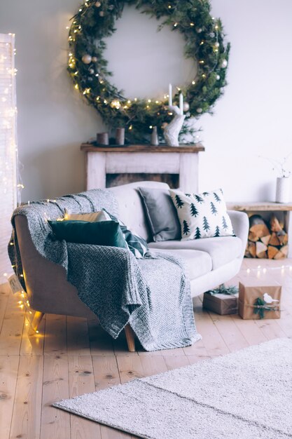 Intérieur de la chambre du nouvel an avec cheminée, canapé et une grande guirlande de Noël au-dessus de la cheminée.