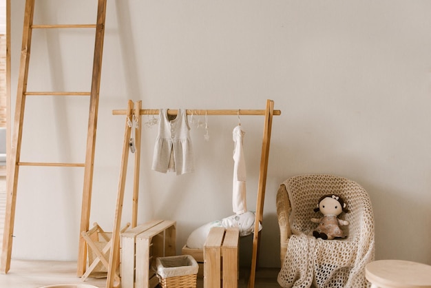 Photo intérieur de chambre d'enfant de style scandinave élégant avec cintre en bois et vêtements de bébé