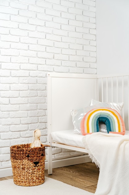 Photo l'intérieur de la chambre des enfants avec un lit confortable et un oreiller arc-en-ciel