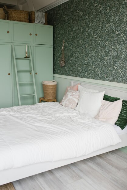 L'intérieur de la chambre est de style moderne. Armoire menthe et lit blanc avec oreillers colorés