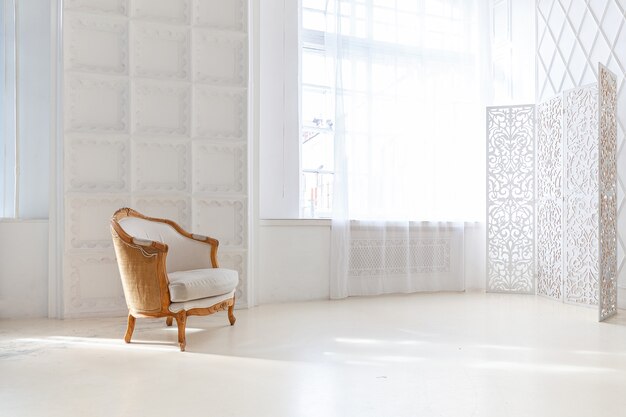 Intérieur de chambre loft élégant. Appartement design spacieux avec des murs clairs, de grandes fenêtres et un fauteuil. Décoration moderne et épurée avec des meubles élégants dans un style scandinave minimaliste.