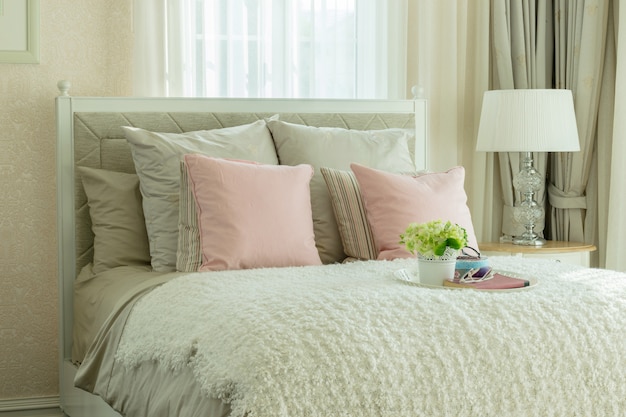 Intérieur de chambre de luxe avec coussins roses et plateau blanc de fleurs sur le lit