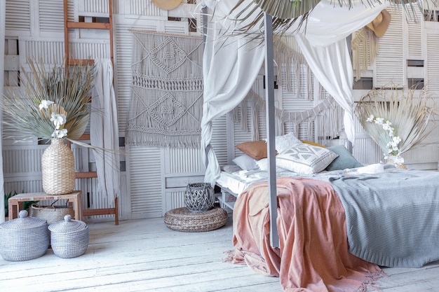 Intérieur de chambre de style balinais. lit à baldaquin avec beaucoup de textiles pour la décoration et articles en osier aux couleurs pastel douces