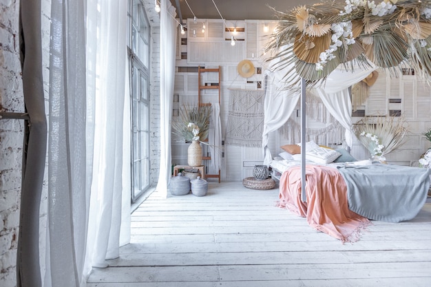 Intérieur de chambre de style balinais. lit à baldaquin avec beaucoup de textiles pour la décoration et articles en osier aux couleurs pastel douces