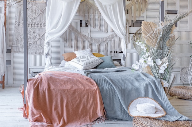 Intérieur de chambre de style balinais. lit à baldaquin avec beaucoup de textiles pour la décoration et articles en osier aux couleurs pastel douces