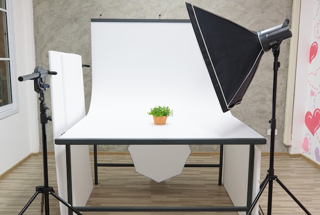 Intérieur avec climatiseur studio blanc table de scène de séance photo et partition avec équipement de photographe professionnel softbox réflecteur flash stroboscopique sur trépied prêt pour les produits de prise de vue.