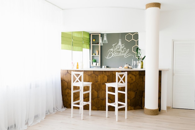 Intérieur confortable du salon avec un comptoir de bar en bois et des chaises blanches