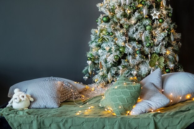 Intérieur confortable à la maison avec des coussins dispersés sous l'arbre de Noël décoré fleuri