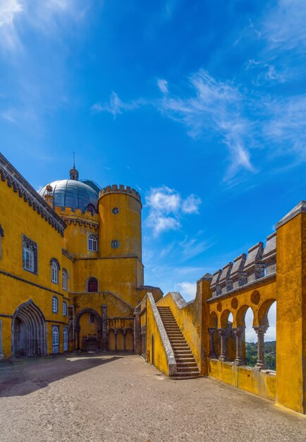 L'intérieur de la cour voûtée avec des escaliers en pierre et les murs peints en jaune du palais de Pena sous un ciel bleu ensoleillé pour l'espace de copie