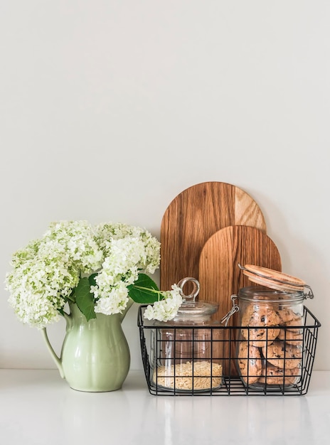 Intérieur de cuisine un bouquet d'hortensias dans une cruche en céramique vintage biscuits dans un bocal planches à découper en chêne sur la table de la cuisine