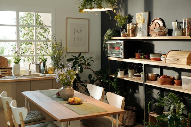 Intérieur de cuisine confortable avec table et chaises au centre contre la fenêtre