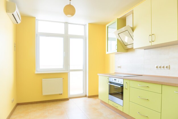 Intérieur de cuisine dans un appartement moderne. Chambre ensoleillée vide jaune clair