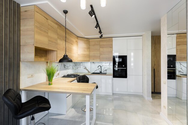 Intérieur d'une cuisine moderne, avec un bar avec des inserts en bois et des carreaux de marbre blanc, dans un petit appartement