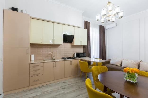 Intérieur d'une cuisine moderne et élégante dans un petit appartement, avec des meubles, dans des couleurs pastel, jaune avec beige