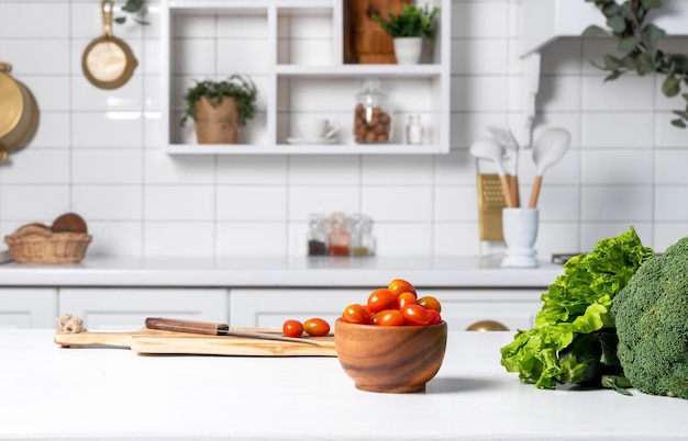 Intérieur de cuisine moderne avec étagères en carreaux blancs, plantes et ustensiles de cuisine sur table murale avec légumes frais