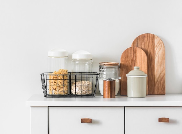 Intérieur de cuisine de style minimalisme boîtes de farine de pâtes dans un panier en métal lave-vaisselle planches à découper sur un tableau blanc