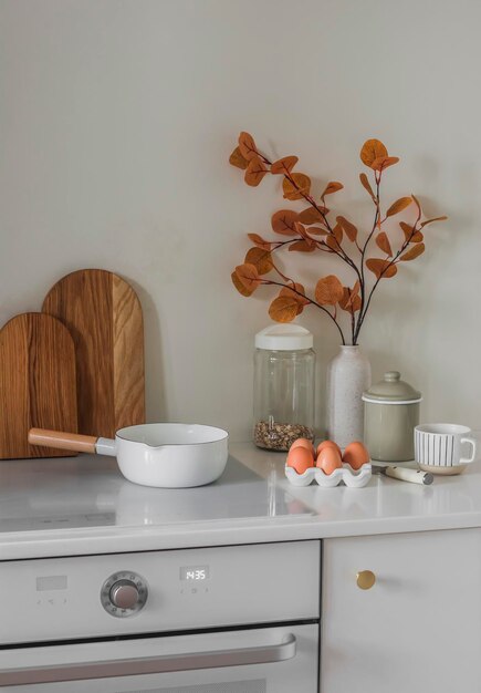 Intérieur de cuisine de style scandinave minimaliste Casserole planches à découper œufs décor d'automne sur meubles de cuisine blancs dans une cuisine lumineuse Préparation du petit déjeuner