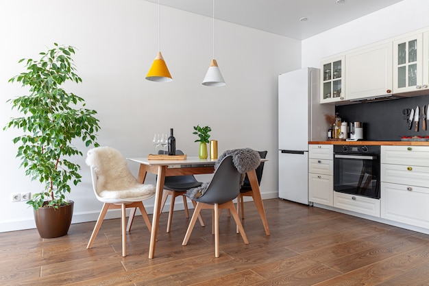 Intérieur design moderne de salle à manger, cuisine, meubles blancs, lampes au-dessus de table en bois, chaises, peau de mouton, arbre, vase, bouteille de vin, verres, concept d'hypothèque, couverture de magazine, horizontal