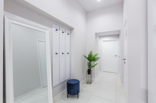 Intérieur du couloir, dans un appartement aux murs blancs et aux portes lumineuses