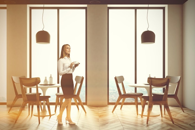 Intérieur du restaurant Loft avec parquet, grandes fenêtres et chaises grises et en bois près des tables rondes.Une femme d'affaires rendu 3d maquette image tonique