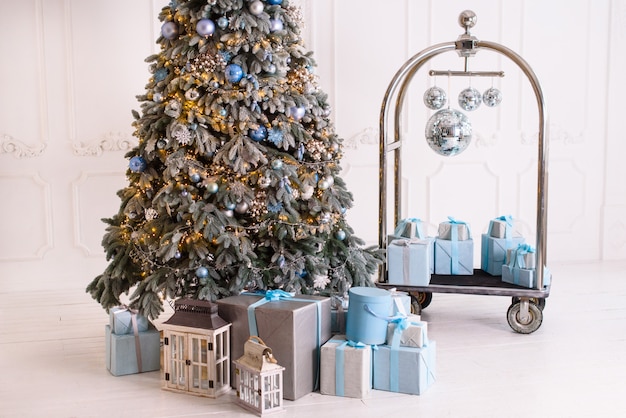 L'intérieur du salon dans le style de Noël avec un grand sapin et des cadeaux de Noël