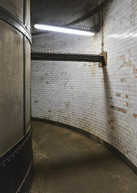 Intérieur du tunnel de pied de Greenwich, murs et sol grunges sales dans un couloir étroit éclairé par un néon.