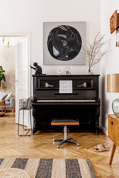 Intérieur élégant et confortable du salon avec piano noir, meubles, plante, horloge en bois, lampe, maquettes de peintures, tapis, décoration et accessoires personnels élégants dans un décor moderne.