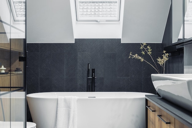 Intérieur élégant de la salle de bain avec baignoire, serviettes de douche et autres accessoires de salle de bain personnels Concept d'intérieur moderne et design Modèle de fenêtre de toit