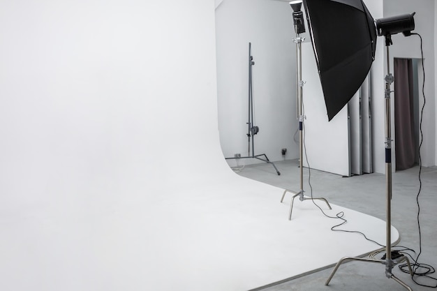 Intérieur de l'espace lumineux du studio photo avec grand cyclorama blanc avec équipement d'éclairage