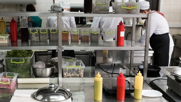 Intérieur de l'espace de travail de la cuisine du restaurant professionnel avec des étagères pleines de produits, de nourriture, de sauces et d'épices