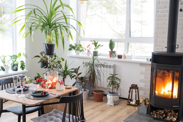 L'intérieur festif de la maison est décoré pour Noël et le Nouvel An dans un style loft avec un poêle à bois noir, un sapin de Noël, un studio chaleureux avec table à bois, confortable et chauffage de la maison