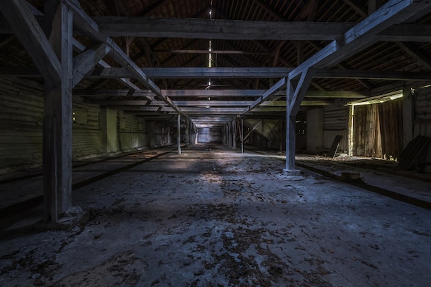 À l'intérieur d'un hangar en bois en ruine abandonné sombre avec des colonnes pourries