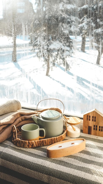 Un intérieur d'hiver confortable, du thé à bougies et une théière sur le rebord de la fenêtre.