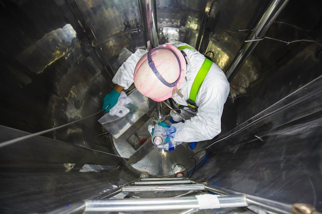 À l'intérieur de l'homme deux travailleurs dans l'air frais du ventilateur chimique en acier inoxydable du réservoir brillant d'inspection