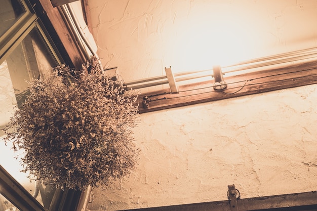 Intérieur de maison avec bouquet de fleurs séchées blanches dans un vase, chambre vintage rustique et minimaliste moderne, lumière sur l'étagère, composition avec des meubles scandinaves en appartement, style minimaliste