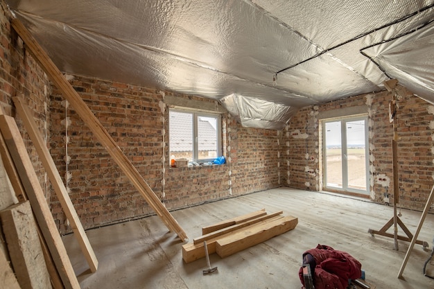 Photo intérieur de maison en brique inachevée avec sol en béton et murs nus en construction