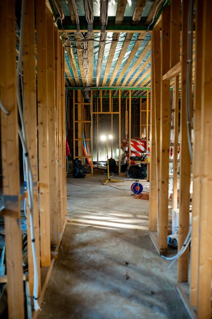 Intérieur de maison en cours de construction avec cadre en bois, câblage électrique et échelle sur place